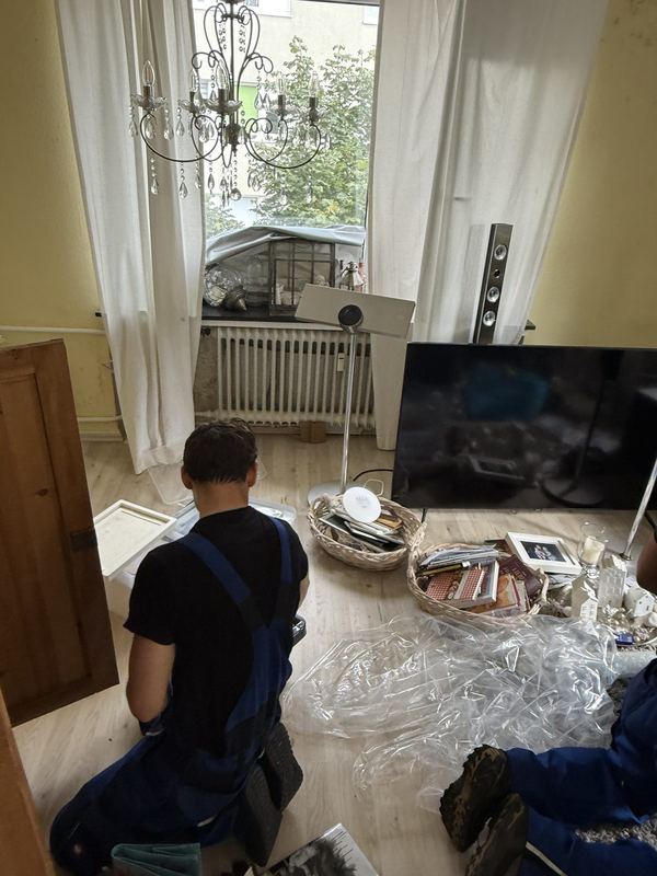 Ein Kollege kniet auf dem Boden und sortiert Hausrat aus Körben und Kisten