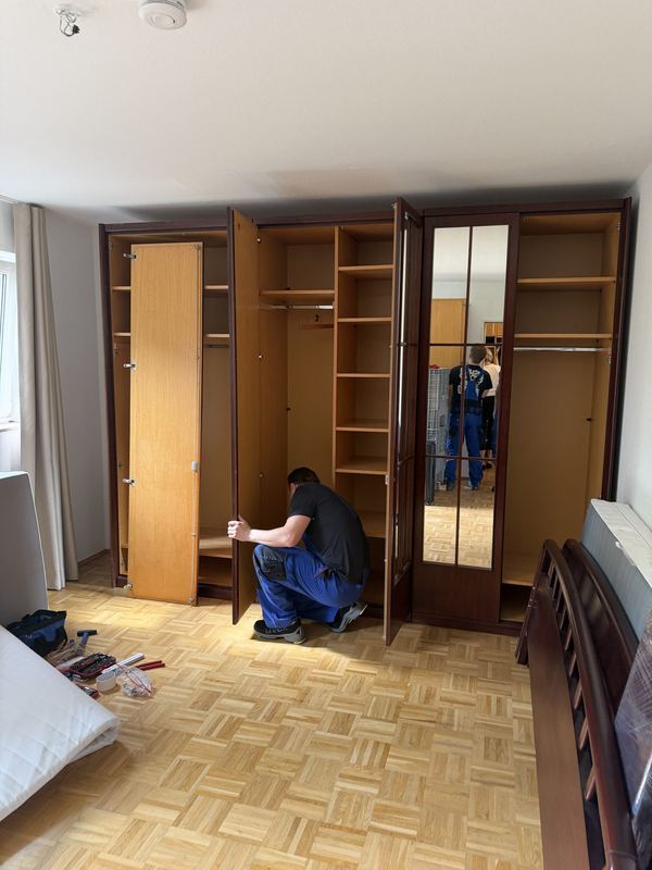 Ein Kollege justiert die Türen eines mehrtürigen Kleiderschranks in einem Schlafzimmer