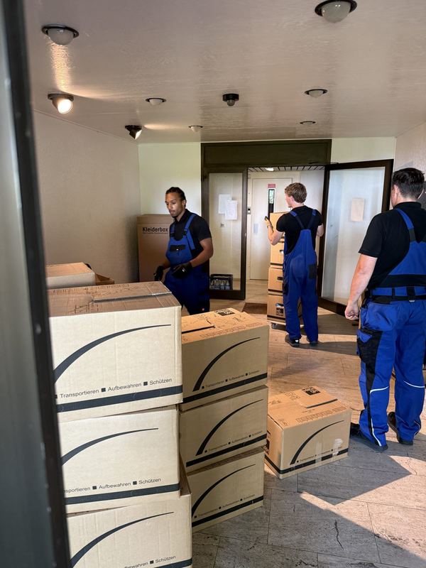 Mehrere Kollegen stellen im Flur Umzugskartons zusammen