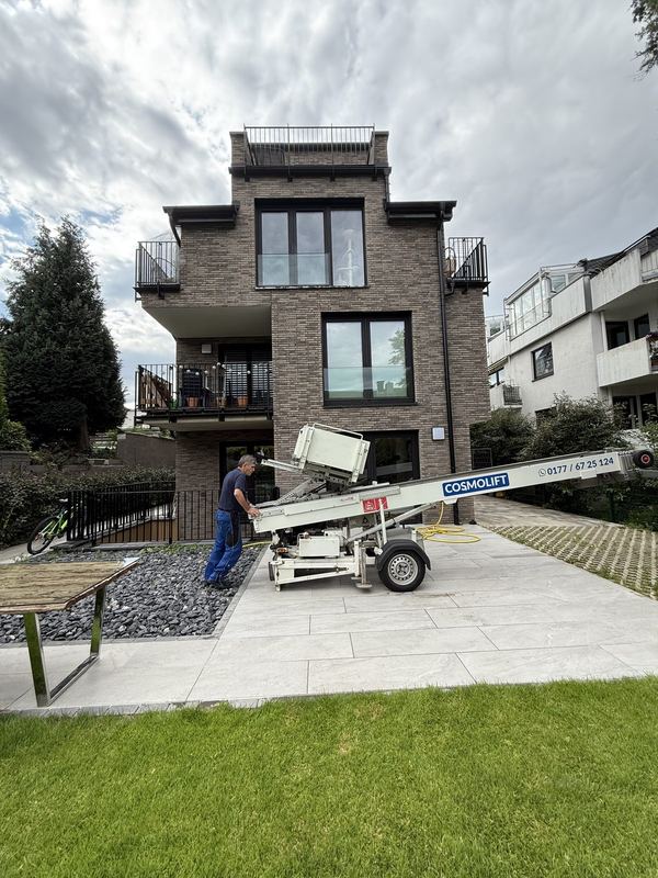 Ein Kollege richtet einen Möbellift auf der Einfahrt vor einem Wohnhaus aus
