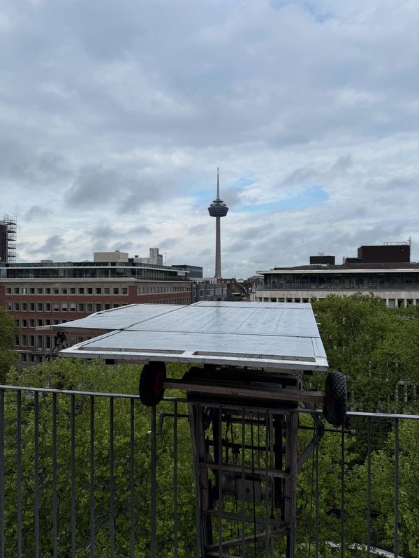 Die Plattform eines Möbellifts auf Höhe eines oberen Stockwerks, im Hintergrund ein Fernsehturm