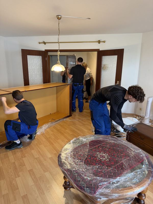 Vier Monteure bauen zusammen das Gerüst einer großen Schrankwand auf