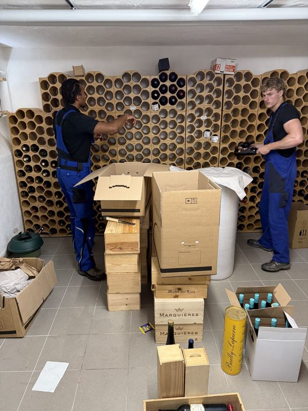 Weinflaschen aus dem Kellerregal in Bergisch Gladbach verpacken Zwei Kollegen räumen Weinflaschen aus einem Kellerregal aus Tonröhren und setzen sie in Holzkisten und Kartons