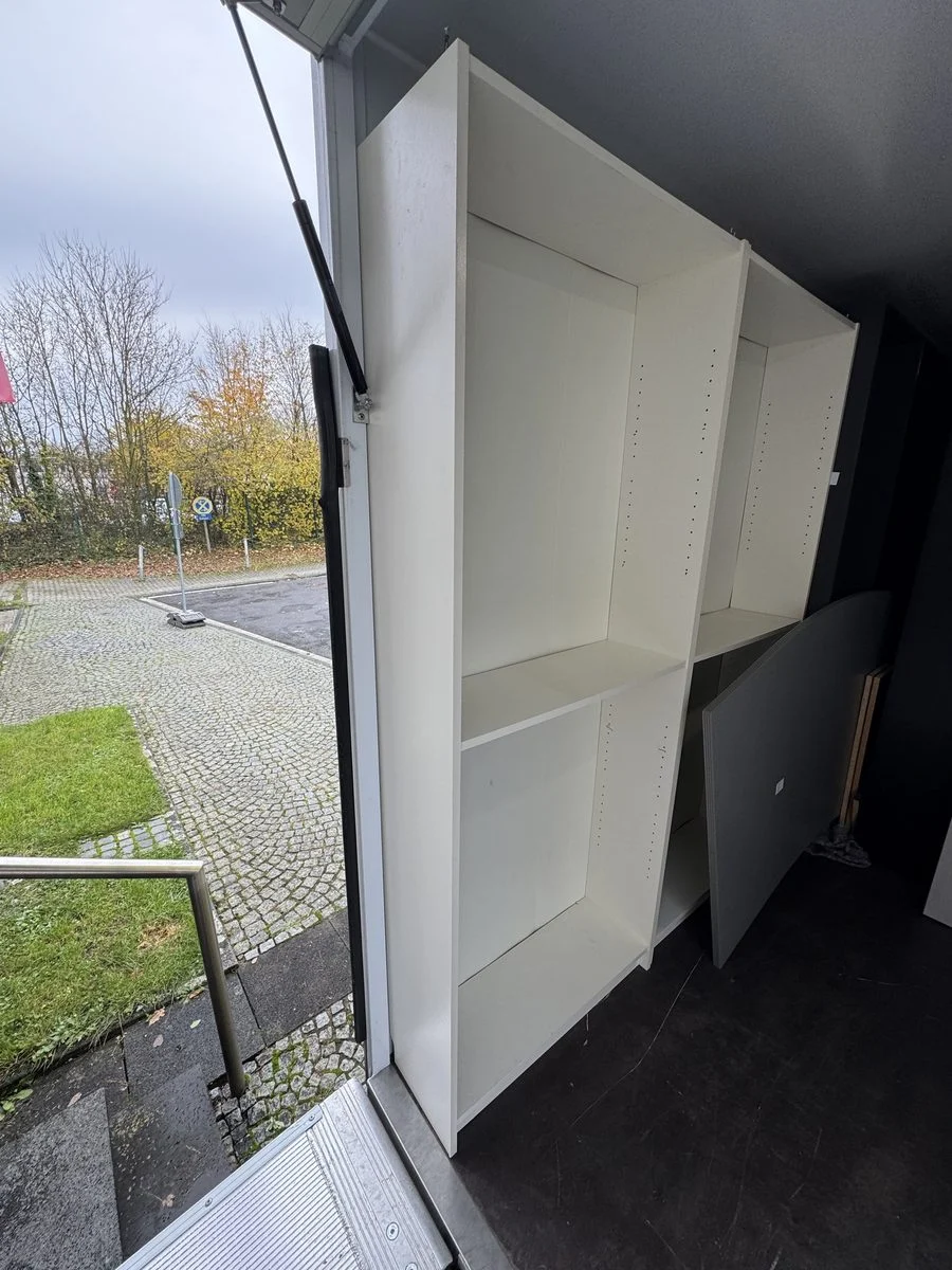 Ein offener, leerer Kleiderschrank steht im Laderaum eines LKW und ist für die Fahrt gesichert.
