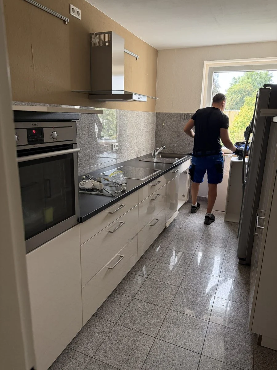 Ein Umzugshelfer arbeitet seitlich an einer Küchenarbeitsplatte während der Montage der Küche.