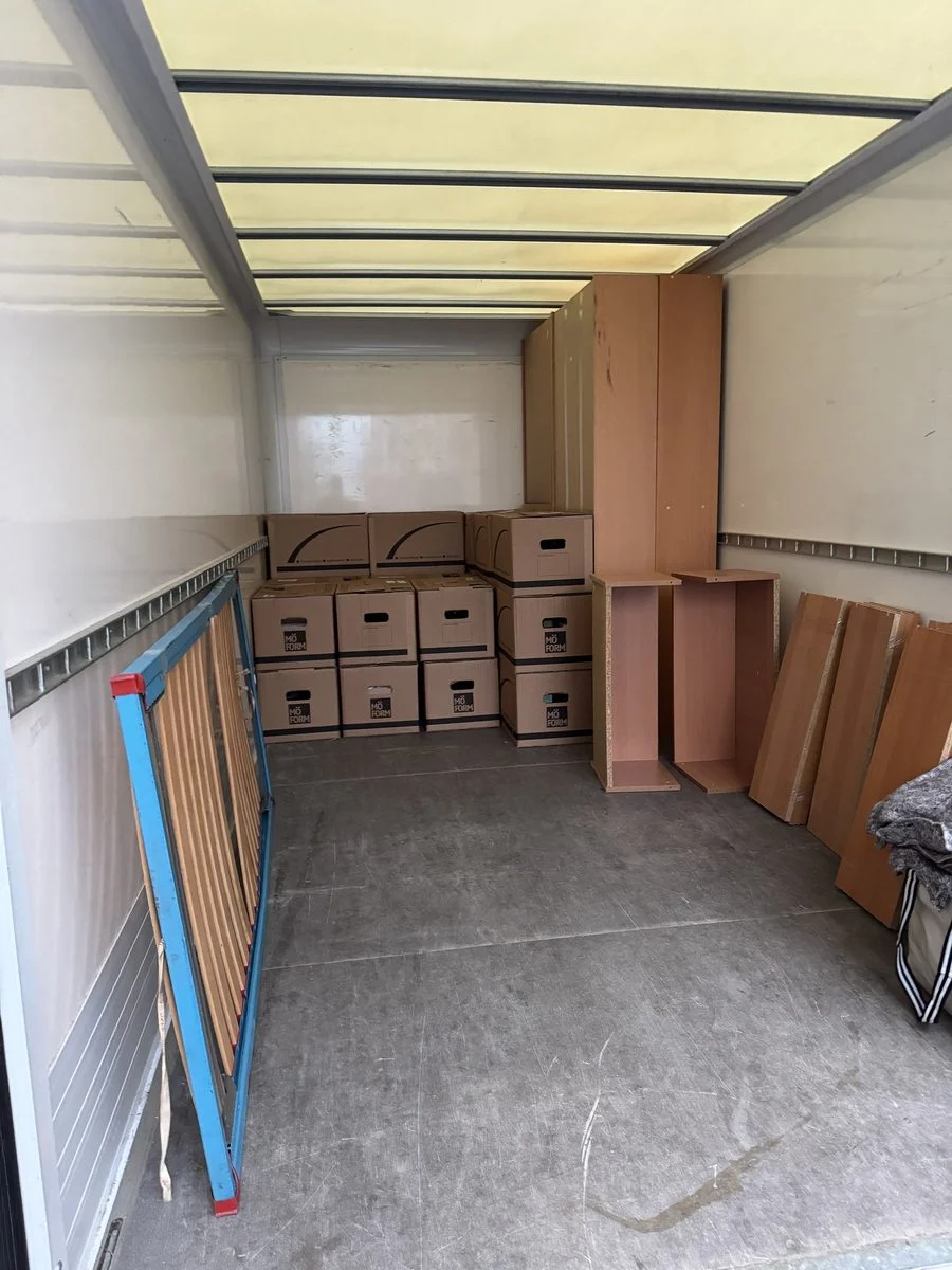 Im Laderaum eines LKW stehen Kartons, daneben sind Klappstühle an der Wand gesichert.