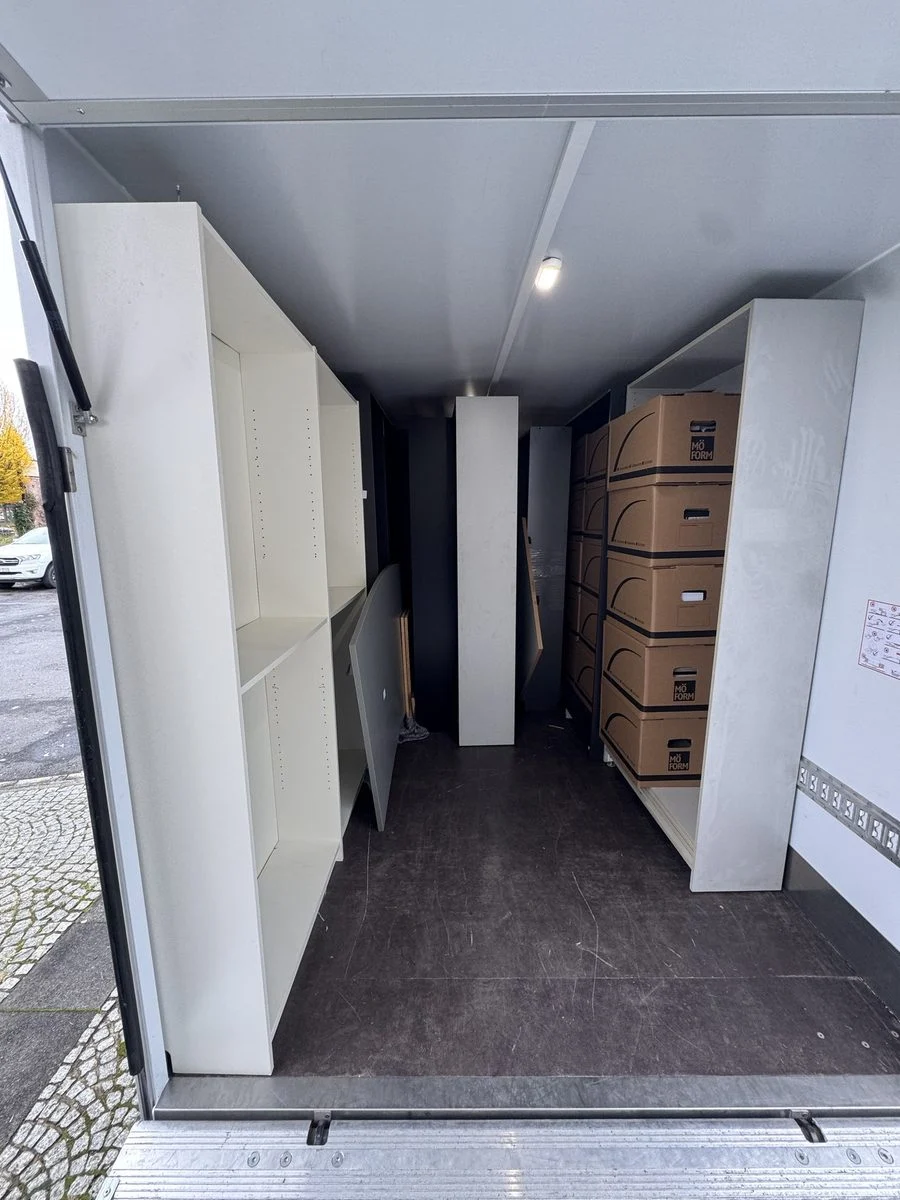 Der Blick durch die offenen Türen eines LKW zeigt den Laderaum, der mit Schränken beladen ist.