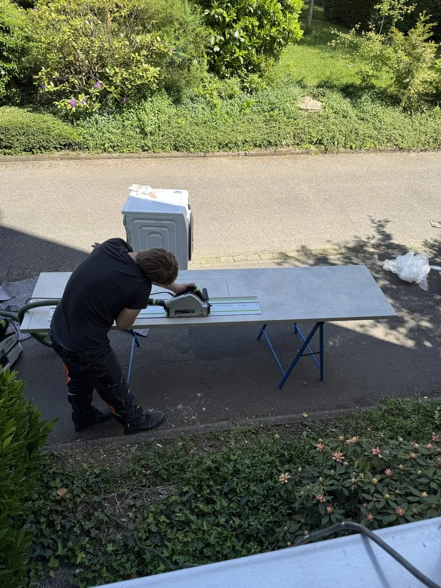 Ein Umzugshelfer schiebt eine Sackkarre mit einer Kiste über die Straße zum bereitstehenden Fahrzeug.
