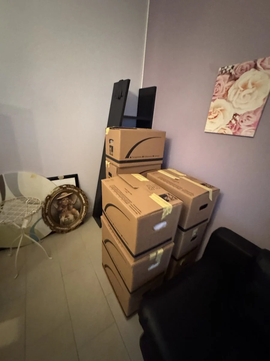 Ein leicht unaufgeräumtes Zimmer mit Kartons und einem Lautsprecher, aufgenommen mitten im Packvorgang.